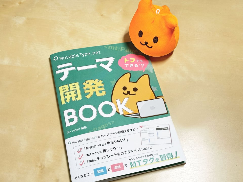 シックス・アパートのキャラクター「トフ」が、「トフでき テーマ開発」の冊子と共に写っている写真